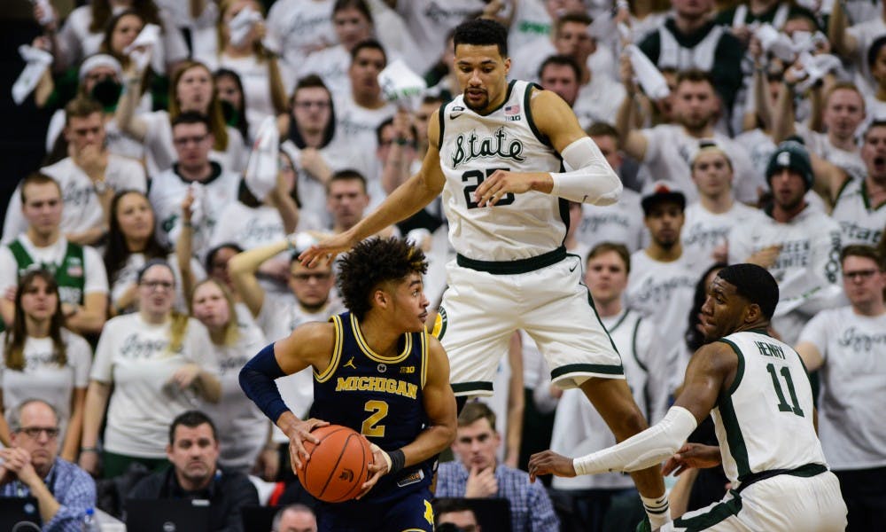 Senior forward Kenny Goins (25) jumps over Michigan forward Jordan Poole (2) during the first half of the game against Michigan at Breslin Center, March 9, 2019.