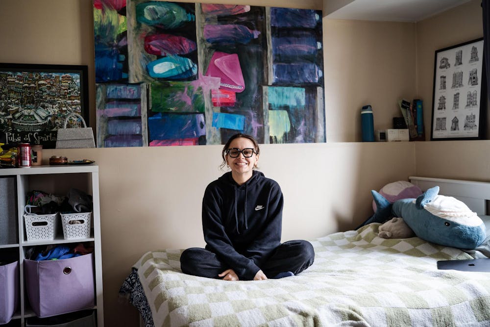 Fourth-year Michigan State studio art student Evan Yalowitz sits on her bed in front of one of her larger paintings on April 13, 2025. Yalowitz described the close connection to her work, saying, “I like to live with my art.”