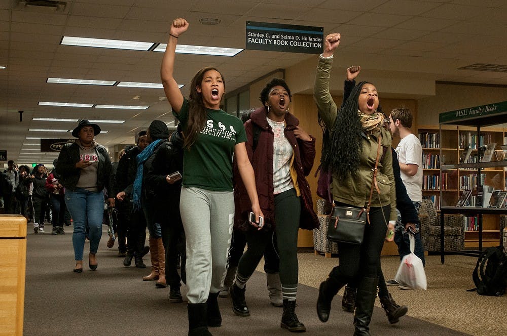 <p>Lyman Briggs and human biology senior Chantelle Washington, left, leads the march with other protesters Dec. 7, 2014, during a die-in protest at the MSU Library. "It is sad that we have to be lying dead in the streets to be relevant," Washington said. The group of students blocked the entrances and walk ways in the library and marched afterwards in protest of police violence against black people while other MSU students were present to study for finals week. Raymond Williams/The State News</p>