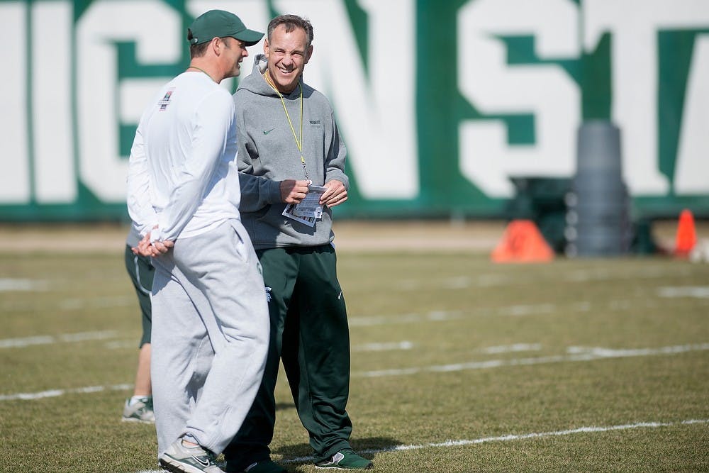 <p>Head coach Mark Dantonio and quarterbacks coach/recruiting coordinator Brad Salem chat during football practice April 8, 2014, at the practice field outside Duffy Daugherty Football Building. Julia Nagy/The State News</p>