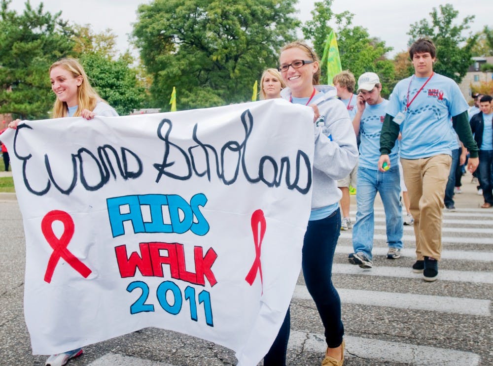 Kinesiology freshman Kayla Hamby, left, and hospitality business freshman Kirsten Gutowski, right, carry the banner for the Evans Scholars on Sunday for the Lansing area Aids Walk. The Evans Scholars have participated in the annual event for several years. Mo Hnatiuk/The State News