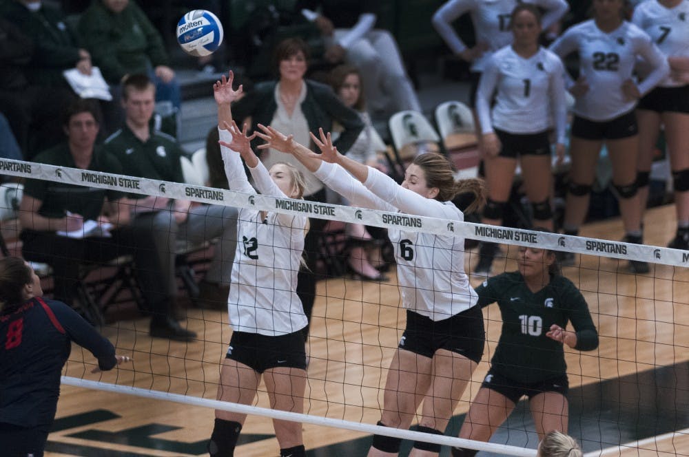 Junior setter Rachel Minarick (12) and senior middle blocker Allyssah Fitterer (6) jump up to block the ball during the game against Arizona on Dec. 3, 2016 at Jenison Field House. The Spartans were defeated by the Wildcats, 3-2.