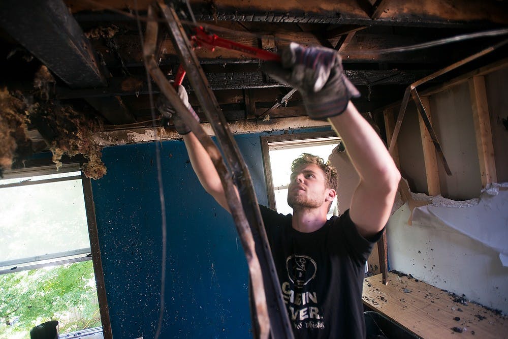 	<p><span class="caps">MSU</span> alumnus Zack Slizewski cuts down metal framing hanging from the ceiling in a room damaged by an early morning fire at Phoenix cooperative, 239 Oakhill Ave, on Sept. 4, 2013. </p>