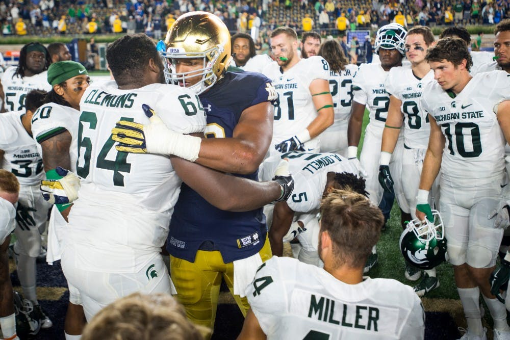 Senior offensive guard Brandon Clemons (64) embraces Notre Dame tight end Alizé Jones (10) after the game against Notre Dame on Sept. 17, 2016 at Notre Dame Stadium in South Bend, Ind. The Spartans defeated the Fighting Irish, 36-28.