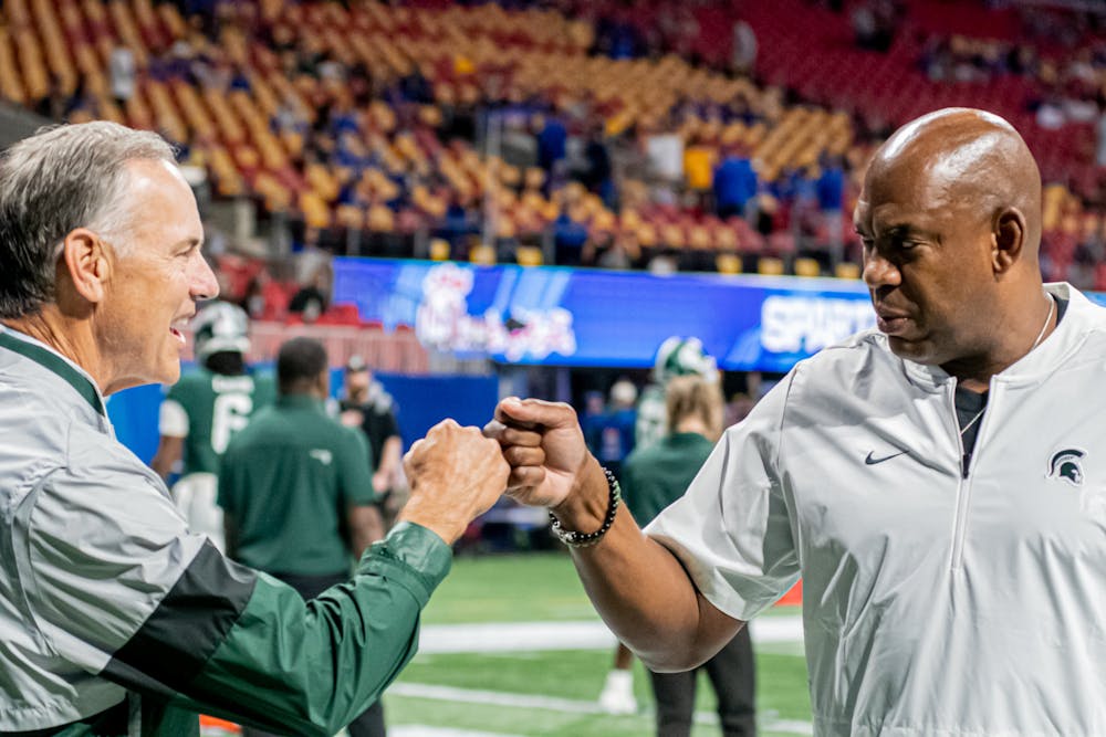 <p>Michigan State head coach Mel Tucker greets former Spartan head coach Mark Dantonio at the Peach Bowl on Dec. 30, 2021.</p>