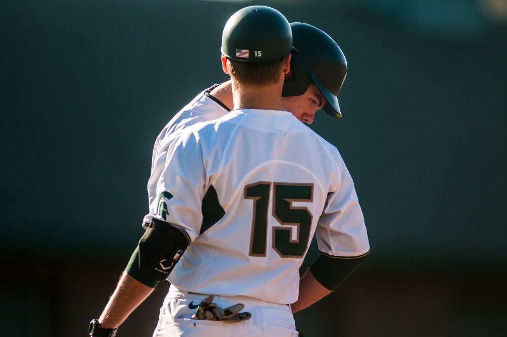 Volunteer assistant coach Jordan Keur talks with sophomore outfielder Brandon Hughes after reaching first base during the game against Michigan on April 12, 2016 at McLane Stadium. 