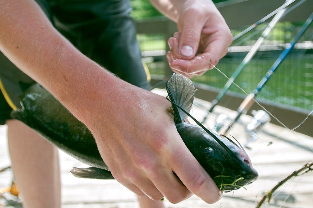 	<p>Okemos resident Josh Hossink, 15, unhooks a catfish from his line on July 10, 2013 at Hawk Island Park, 1601 E. Cavanaugh St. Hossink has been a fisherman since the age of 6. Weston Brooks/The State News</p>