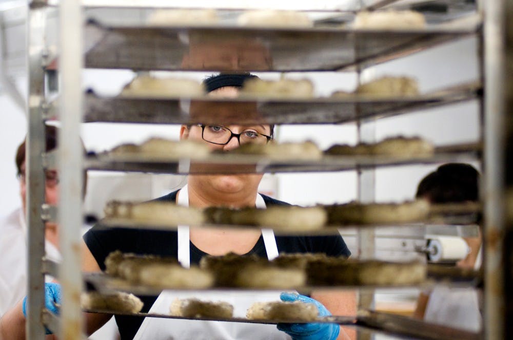 Communications senior Danielle Vanderworp places bagels on a rack before they are baked Monday at the MSU Food Stores. Vanderworp and the rest of the MSU Bakers prepare and provide food daily for students and staff across campus. Matt Radick/The State News