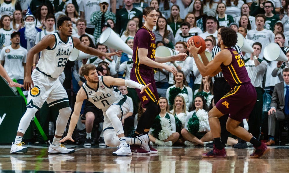 <p>Minnesota's Gabe Kalscheur crosses over senior forward Kyle Ahrens (0). MSU beat Minnesota 79-55 at the Breslin Center on Feb. 9, 2019.</p>