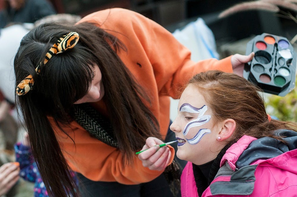 	<p>James Madison senior Shelby Iseler paints the face of St. Johns, Mich., resident Katie Marsh, 10, at the Lansing City Market on Oct. 26. 2013. Kids also got the opportunity to paint pumpkins and pet various animals. Khoa Nguyen/The State News</p>