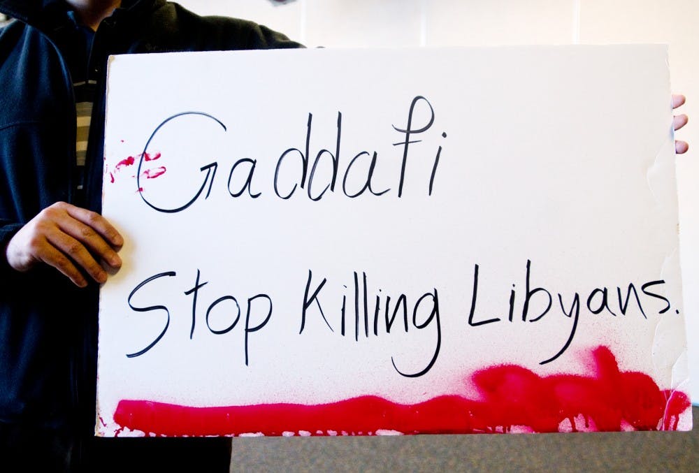 A Libyan MSU student holds a sign of protest Tuesday at the International Center. Students gathered to discuss the current crisis in Libya, where people have taken to the streets in hopes of overthrowing current ruler Muhamar al-Gaddafi. Matt Radick/The State News