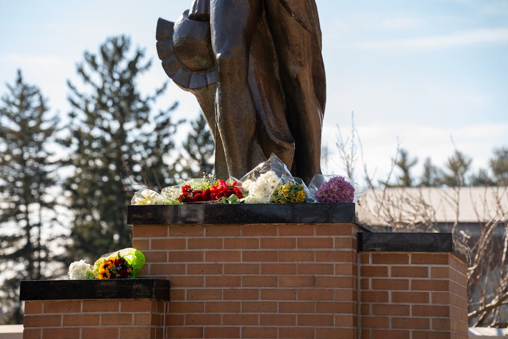 Flowers sit at the foot of the Spartan statue on Feb. 14, 2023, one day after a mass shooting took place in Michigan State University's North Neighborhood.