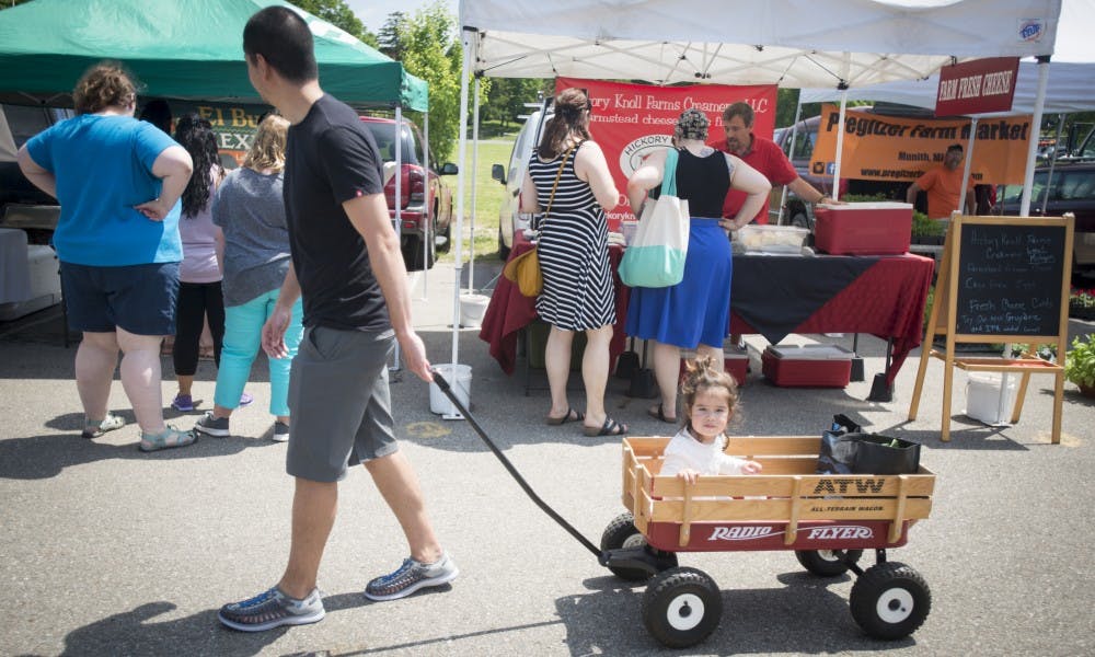 <p>East Lansing resident Troy Fassbender takes his daughter Mariko Fassbender shopping during the East Lansing Farmer's Market on June 4, 2017 at Valley Court Park. The East Lansing Farmer's market is a growers-only market and every item sold by vendors is homegrown.&nbsp;</p>