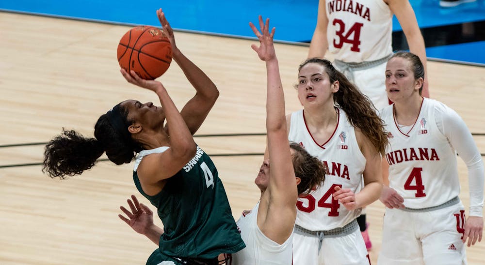 <p>Then-senior forward Alisia Smith (4) dodges an Indiana defender as she jumps up to score during the first quarter. The Spartans advanced to the semifinals of the Big Ten tournament after defeating the Hoosiers 69-61 at Bankers Life Fieldhouse. Shot on Mar. 11, 2021.</p>