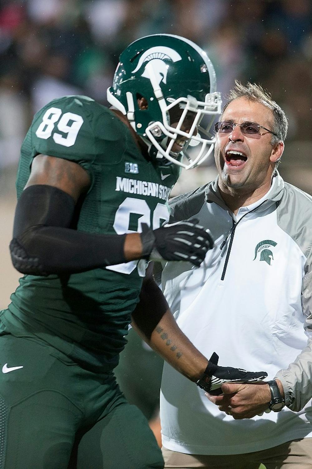 <p>Assistant head coach/defensive coordinator Pat Narduzzi low fives junior defensive end Shilique Calhoun before the game against Nebraska on Oct. 4, 2014, at Spartan Stadium. The Spartans defeated the Huskers, 27-22. Julia Nagy/The State News</p>