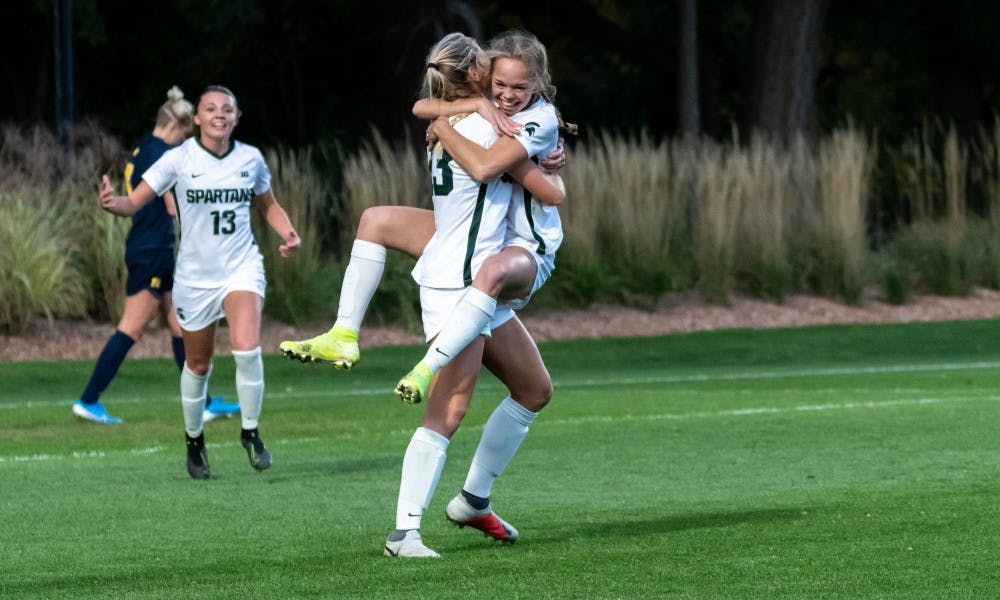 <p>Then-freshman forward Paige Webber (right) celebrates with a teammate after scoring a goal. The Wolverines defeated the Spartans at DeMartin Soccer Stadium, 3-2, on Oct. 19, 2019. </p>