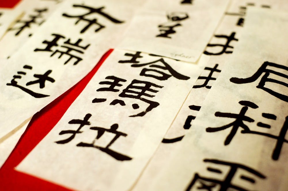 Pieces of paper reading names in Chinese characters lie on the table during Global Festival on Sunday afternoon at the Union. Members of the Chinese Calligraphy Club were creating them throughout the afternoon for festival-goers. Lauren Wood/The State News