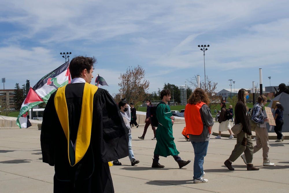 A person attending spring convocation looks at the student protestors outside the Breslin Center on April 26, 2024. The students picketed the event, demanding MSU divest from Israel. 
