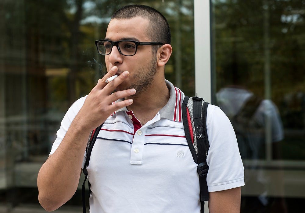 <p>Mechanical engineering junior Saeed Alkhunaizi takes a cigarette break Sept. 29, 2014, between studying outside of the Main Library. Erin Hampton/The State News</p>