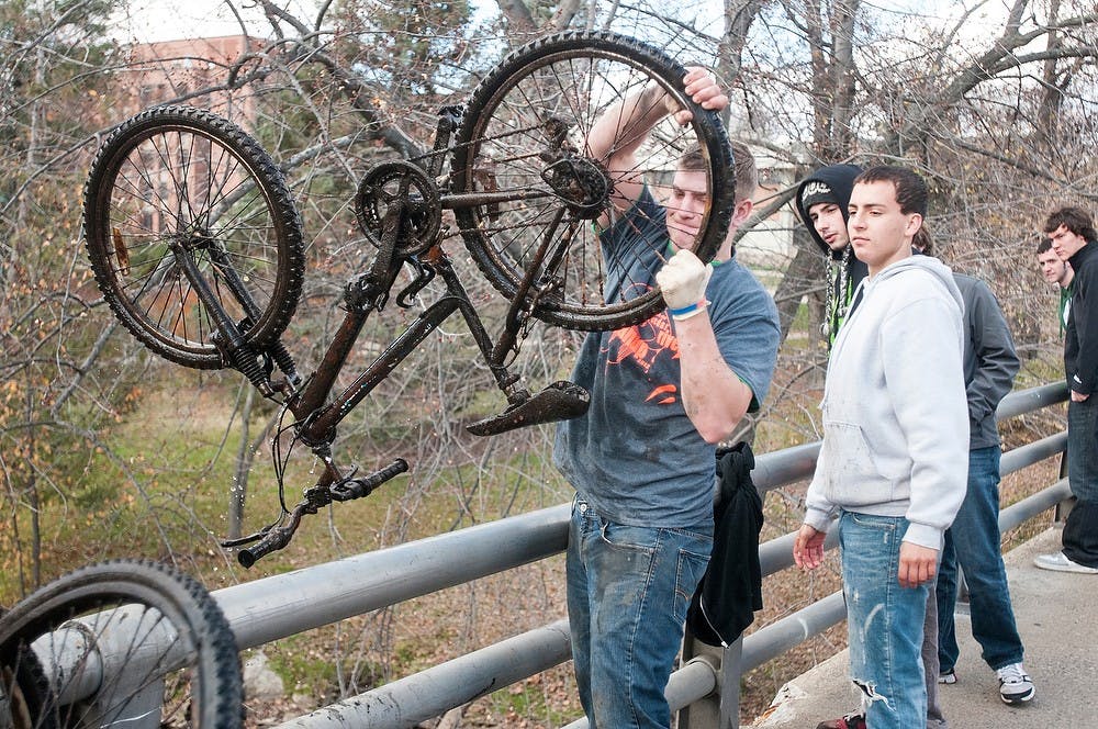 Holland, Mich., resident Travis Dreyer pulls out a bike from the Red Cedar River  on Oct. 27, 2012, on campus. The river cleanup event is held by the MSU Fisheries and Wildlife Club twice a year. A grand total of 60 bikes were removed from the river. Katie Stiefel/State News