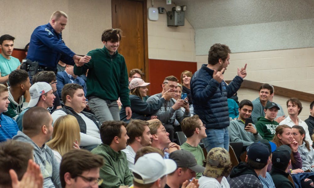 <p>Two members of the audience are escorted out by police after shouting insults at Turning Point USA founder Charlie Kirk. Turning Point USA hosted the Michigan State stop of its Campus Clash tour at the Natural Science Building on April 16, 2019.</p>