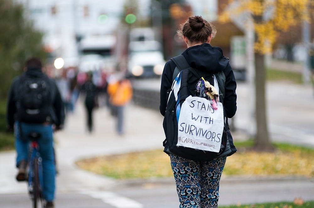 <p>Elementary education sophomore Hayley Penn walks down Farm Lane with a pillow case on her backpack in support of ending rape culture Oct. 29, 2014, in front of the Auditorium. MSU Students United organized this event in support of the victims of rape across the country. Dylan Vowell/The State News</p>