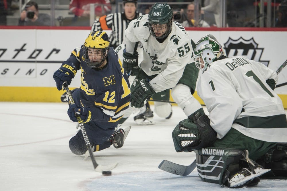 Michigan left wing Dakota Raabe (12) shoots against freshman goaltender Drew DeRidder (1) during the Duel in the D at Little Caesars Arena in Detroit on Feb. 9, 2019. Michigan defeated Michigan State 5-2. Nic Antaya/The State News