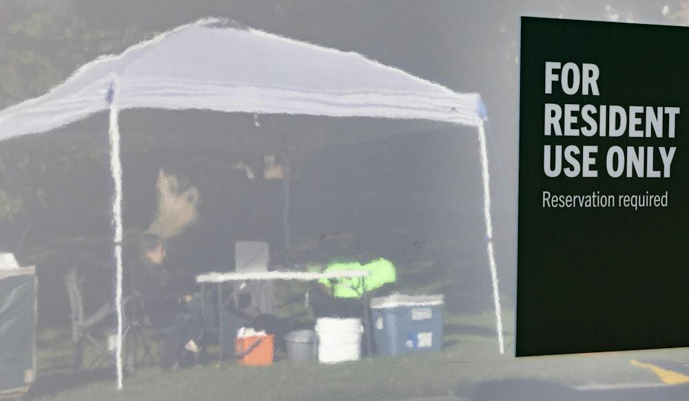 <p>Michigan State Mobile Shower unit Coordinator Ava Leonardis (left) and Centurion Security guard, Micah Rembert (right) sit and wait to assist students to check in for their shower times at the mobile shower units brought on campus in East Lansing, Mich., on Thursday, Sept. 24, 2026.</p>