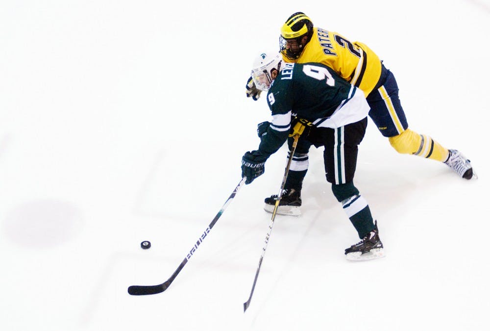 Junior center Daultan Leveille battles for the puck with Michigan defenseman Greg Pateryn during the first period Saturday at Yost Ice Arena in Ann Arbor. MSU fell to U-M, 4-0. Kat Petersen/The State News