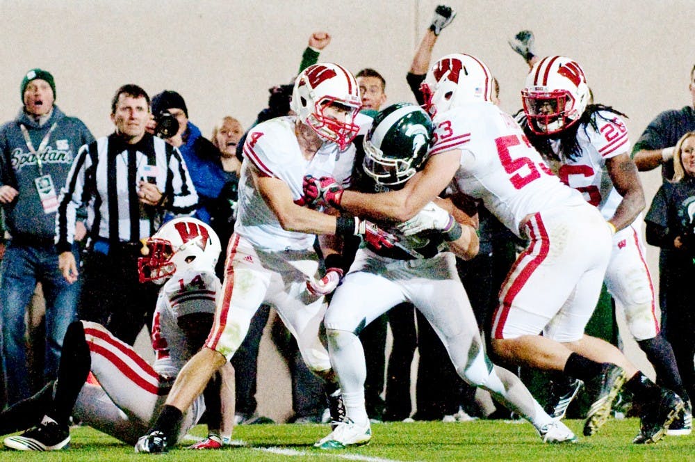 Senior wide receiver Keith Nichol fights with Wisconsin defenders to get the ball in the endzone. After an official review, the play was called a touchdown and as a result MSU won the game. The Spartans defeated Wisconsin, 37-31, on Saturday night at Spartan Stadium. Josh Radtke/The State News