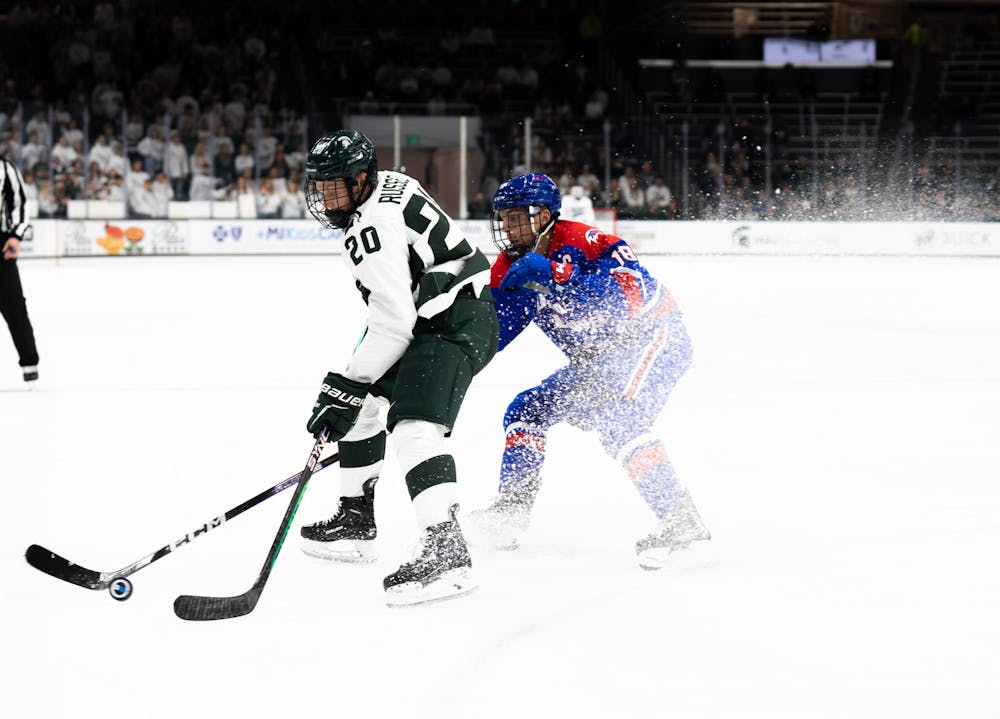 <p>Freshman forward Daniel Russell (20) fights for the puck against UMass during a game at Munn Ice Arena on Oct. 13, 2022. The Spartans defeated the Minutemen with a score of 4-3.&nbsp;</p>
