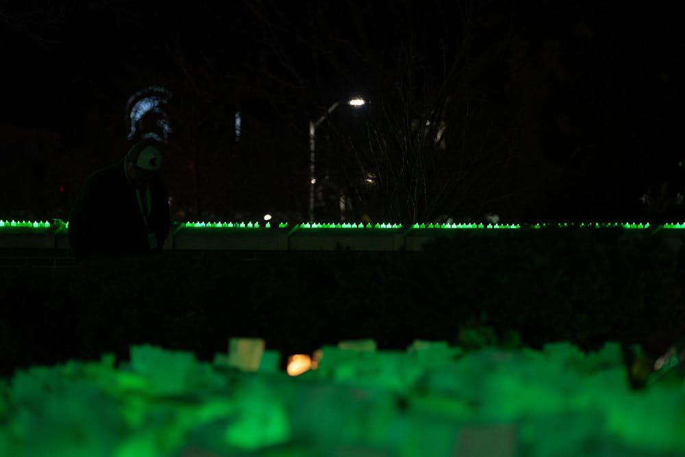 <p>The Spartan Stadium's glowing Spartan head shone through the trees, with the green-lit and luminary-filled Spartan Statue nearby on Feb. 13, 2024. One year after the Michigan State University campus shooting, a remembrance ceremony was held to remember and reflect on the tragedy.</p>