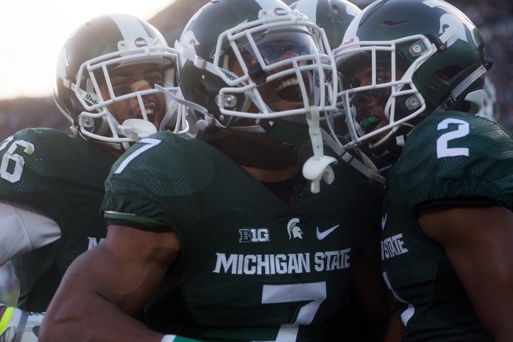 From left to right, senior cornerback Arjen Colquhoun, 36, junior defensive back Demetrious Cox, 7, and junior cornerback Darian Hicks, 2, celebrate after a touchdown made by Cox after a fumble recovery during the second quarter of the game against Penn State on Nov. 28, 2015 at Spartan Stadium. The Spartans defeated the Nittany Lions, 55-16. 