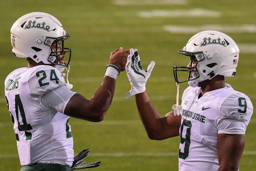 Running back duo Elijah Collins (24) Kenneth Walker III (9) do a handshake prior to the Spartans game against Northwestern. Michigan State won the season opener at Ryan Field 38-21, on Sep. 3, 2021.