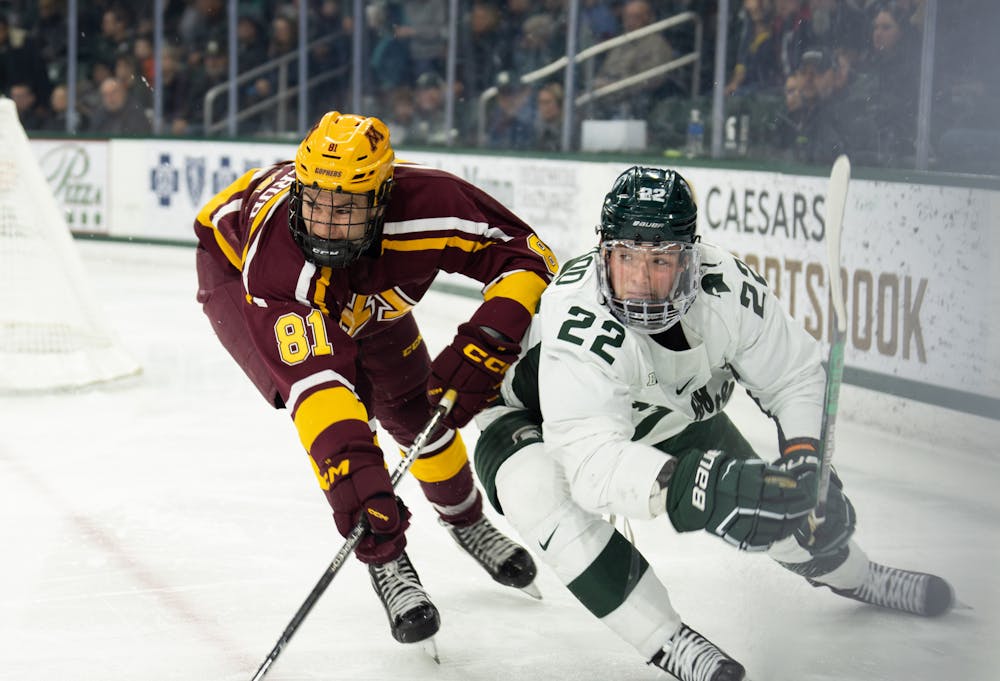 <p>Graduate defenseman Michael Underwood (22) fights off University of a Minnesota player at Munn Ice Arena on Dec. 2, 2022. The Spartans lost to the Gophers with score 5-0. </p>