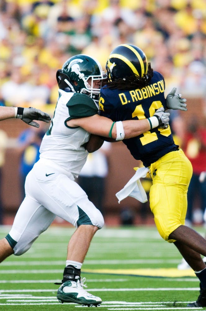 Senior linebacker Eric Gordon tackles Michigan quarterback Denard Robinson as he attempts to scramble Saturday afternoon at Michigan Stadium in Ann Arbor. Robinson had a season low of only 86 yards rushing against Spartan defense. Sam Mikalonis/The State News