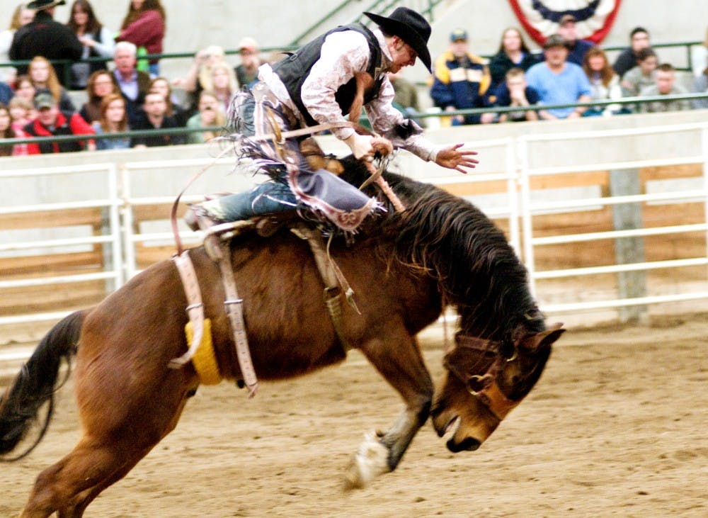 Rider Dave Doyon of St. Victor, Quebec, looks to stay balanced during the saddle bronc riding event Friday night at the Pavilion, 4301 Farm Lane. In this event there is nothing to hold onto so the rider must stay on the saddle through timing and balance. Jaclyn McNeal/The State News