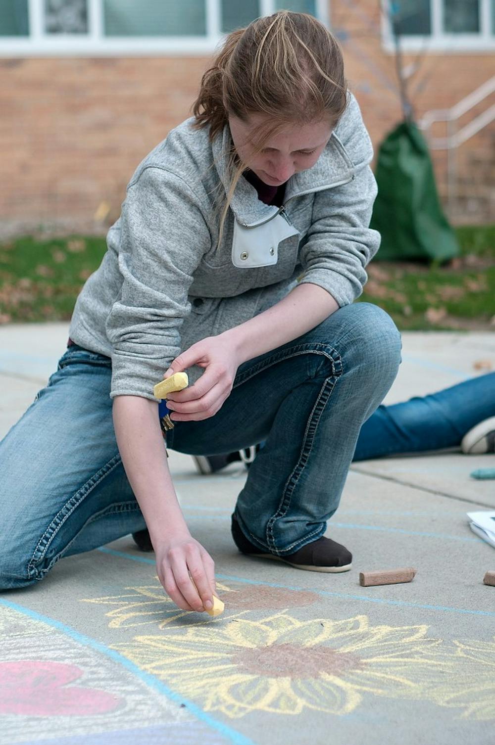 <p>Doctoral student Kate Glanville draws with chalk April 22, 2014, outside Bailey Hall. She helped create a mandala with the RISE program that supported taking care of the environment. Betsy Agosta/The State News</p>