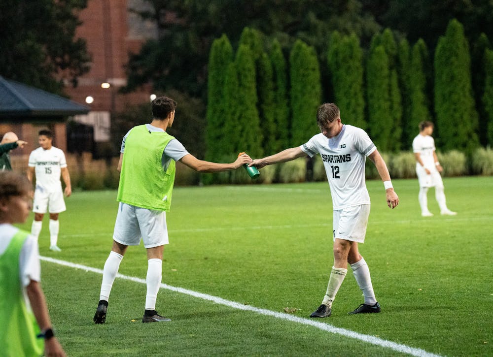 <p>Senior defense Nick Stone accepts a water bottle from a fellow Spartan during the match against Notre Dame on Aug. 29, 2022.</p>