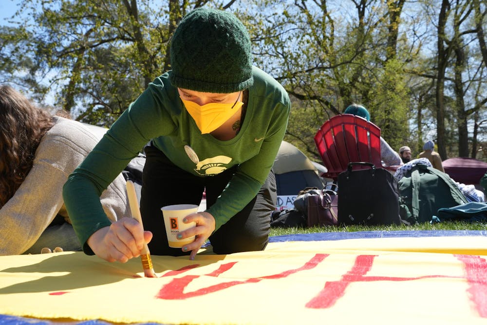 A student paints on a banner during a Gaza solidarity encampment in People’s Park on April 25, 2024.