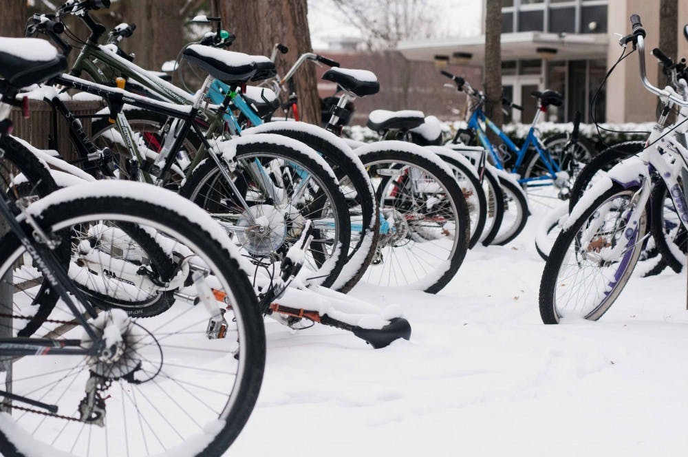 Bike racks between Holmes Hall and McDonel Hall hold many snow-covered bikes on Jan. 14, 2018. Some students have opted for warmer ways to get to class. (State News | Annie Barker)