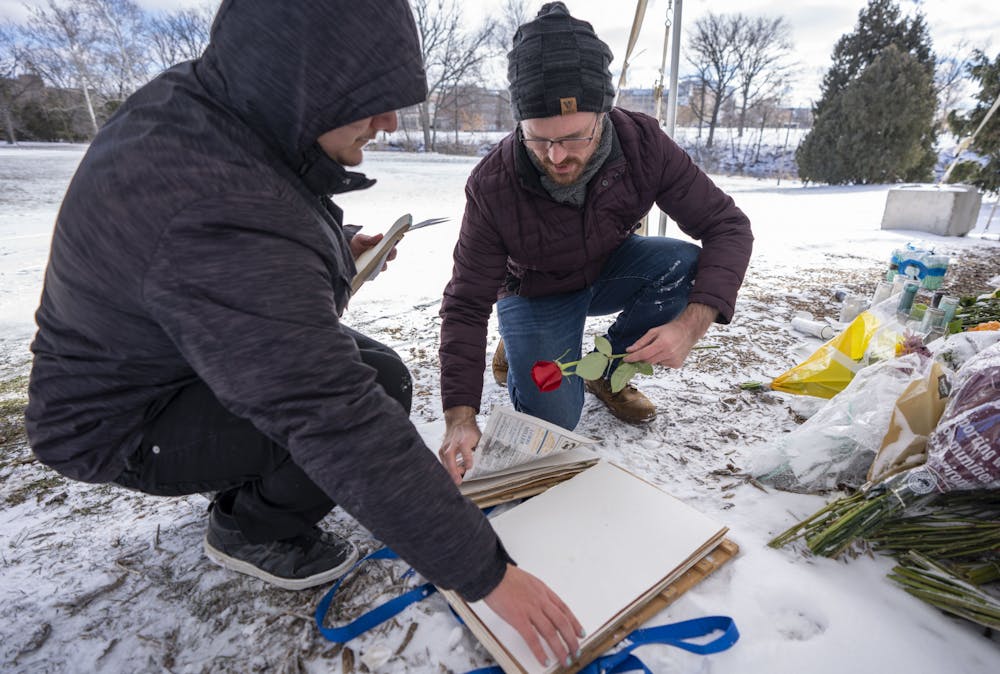 Matt Chansler, a collections assistant for the MSU Herbarium, works with Jordan Zapata, a plant biology junior, to collect flowers from the memorial at the Rock on Farm Lane on Friday, Feb. 17, 2023. “We wanted to pull these so they can be preserved in perpetuity before they’re removed or anything else happens to them,” Chansler said. 