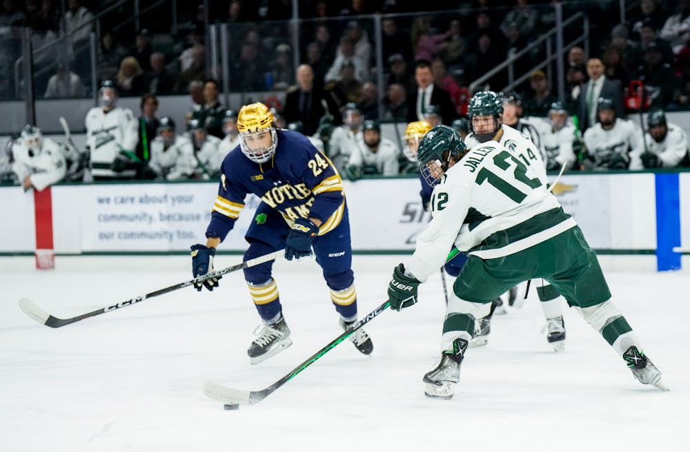 <p>Graduate student forward Justin Jallen (12) dribbles the puck during a game against Notre Dame at Munn Ice Arena on Feb. 3, 2023. The Spartans defeated the Fighting Irish 3-0.</p>