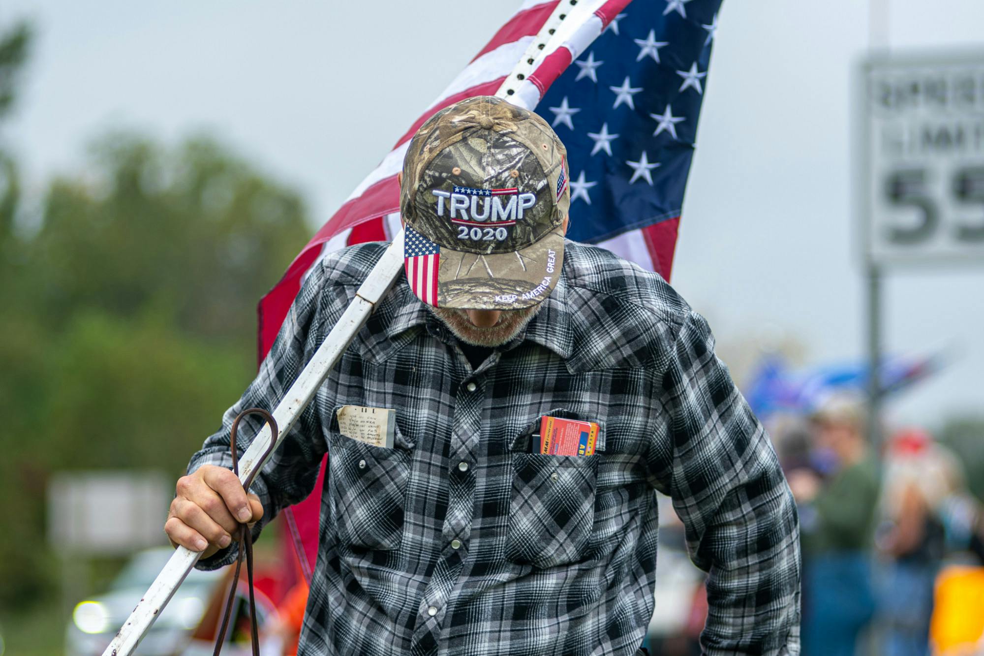 <p>A man walks with an American flag and Trump hat on Oct. 5, 2021, at the &quot;Stop the Spending&quot; protest in Howell. </p>