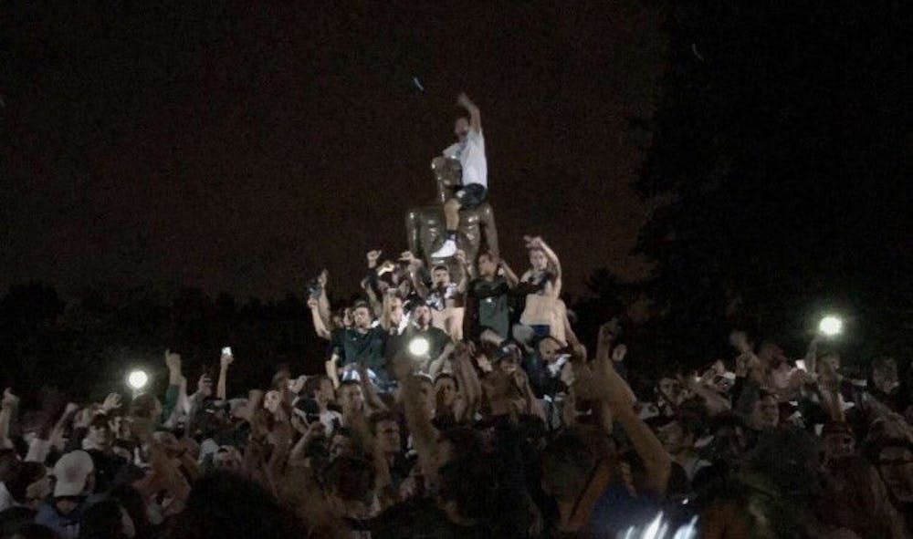 <p>MSU fans celebrate the Spartan's 14-10 victory over U-M Oct. 7 by swarming the Spartan Statue. Photo courtesy of Sasha Zidar.</p>