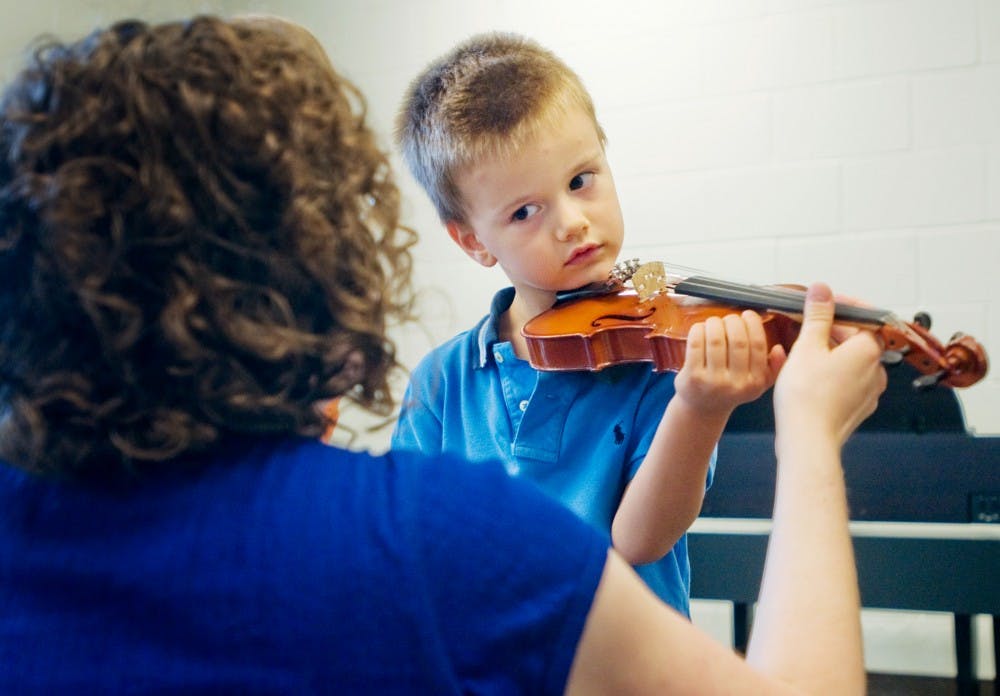 Lauren Hansen, left, instructs Marin Zegarac, 5, on the proper way to hold a violin on Sunday during the Community Music School's fall open house.  Mo Hnatiuk/The State News