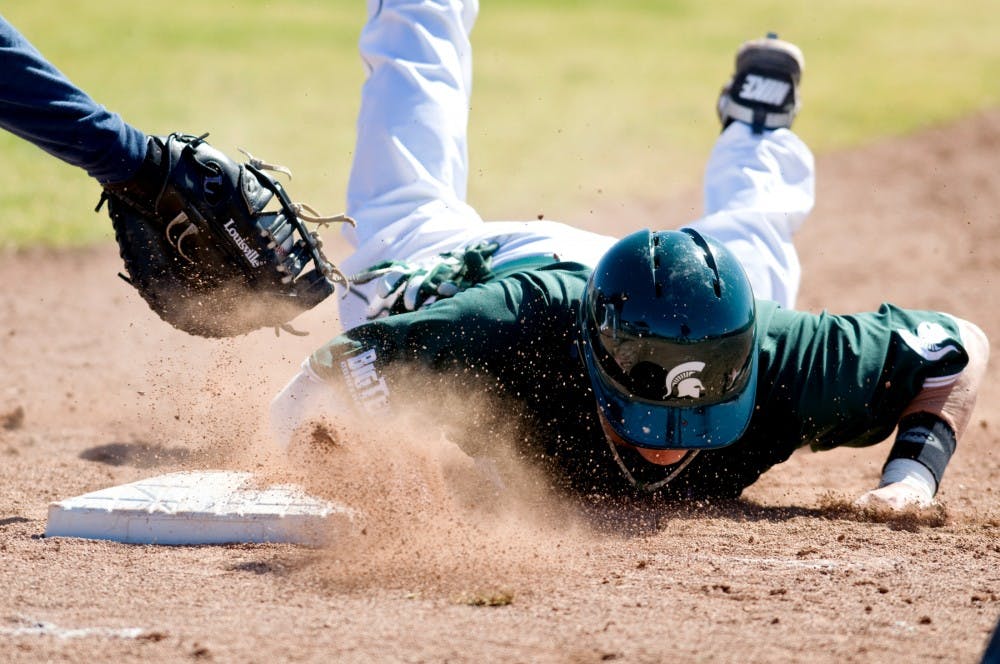 Sophomore designated hitter Jared Hook beats Michigan first baseman Garrett Stephens' tag as he slides back to first base Sunday at Ray Fisher Stadium at Wilpon Baseball Complex in Ann Arbor. The Spartans defeated the Wolverines 5-4. Matt Radick/The State News