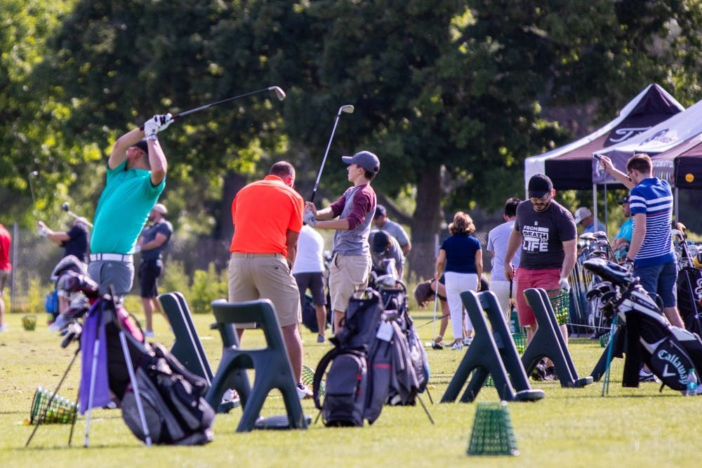 People take their shots on the driving range of Forest Akers East Golf Course on June 14.