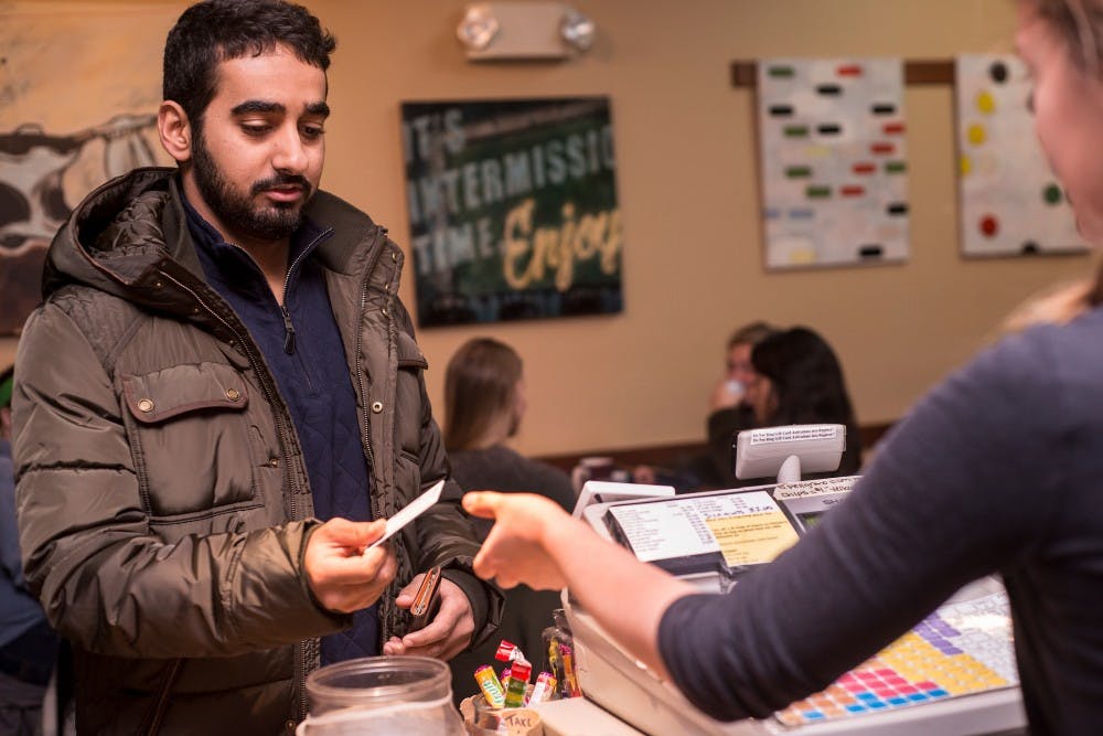 <p>Civil engineering senior Khaled Alghafli pays for his coffee with his Flock Tag card on Nov. 16, 2014, at Espresso Royale, 527 E. Grand River Ave. in East Lansing. Alghafli was awarded a free coffee after he built up enough points on his card. Erin Hampton/The State News</p>