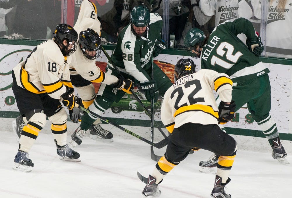 Junior forward Villiam Haag, 26, and senior forward Ryan Keller, 12, fight for the puck against Michigan Tech defenseman Matt Roy, 3, Michigan Tech defenseman Shane Hanna, 22, and Michigan Tech forward C.J. Eick, 18, during the game against Michigan Tech on Nov. 22, 2015 at Munn Ice Arena. The spartans tied with the Huskies, 4-4.